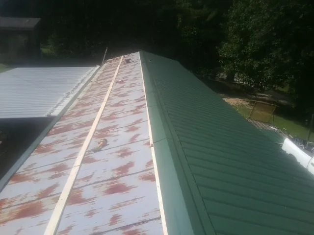 Old rusted panels beside newly installed green metal roofing — Wind Damage Roof Repair by Roofing Brothers in Morton