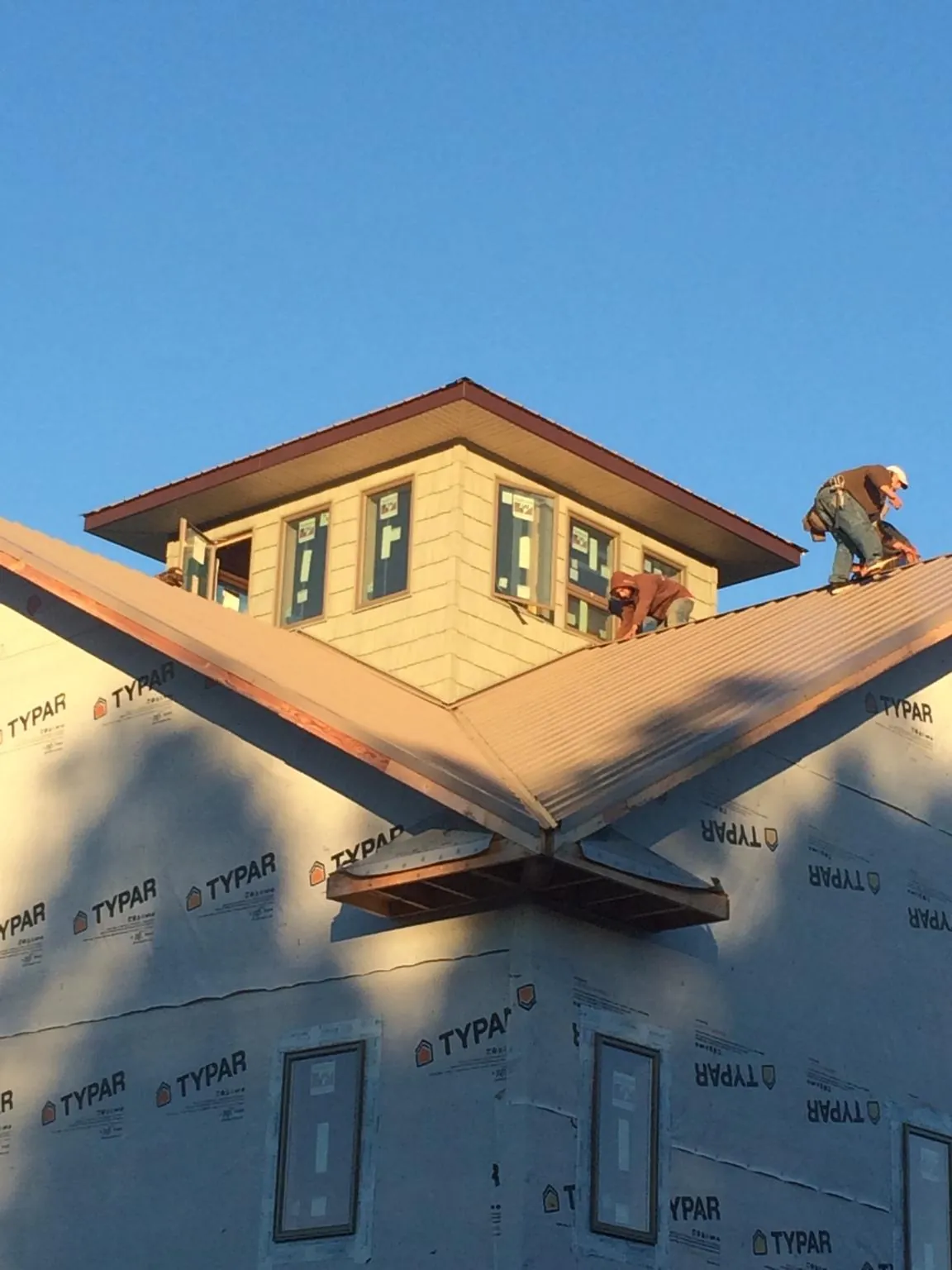 Roofers working around a rooftop cupola on a new metal roof at sunset — Roof Waterproofing in Morton by Roofing Brothers